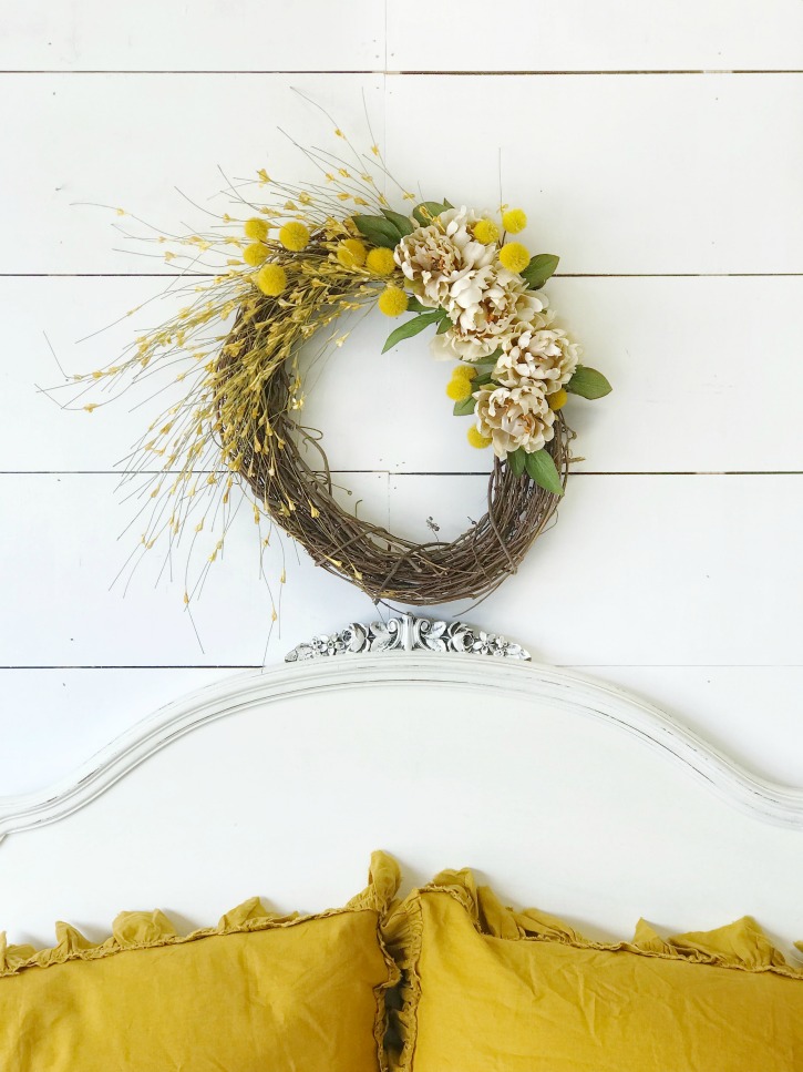 fall wreath above white headboard and 2 yellow pillows